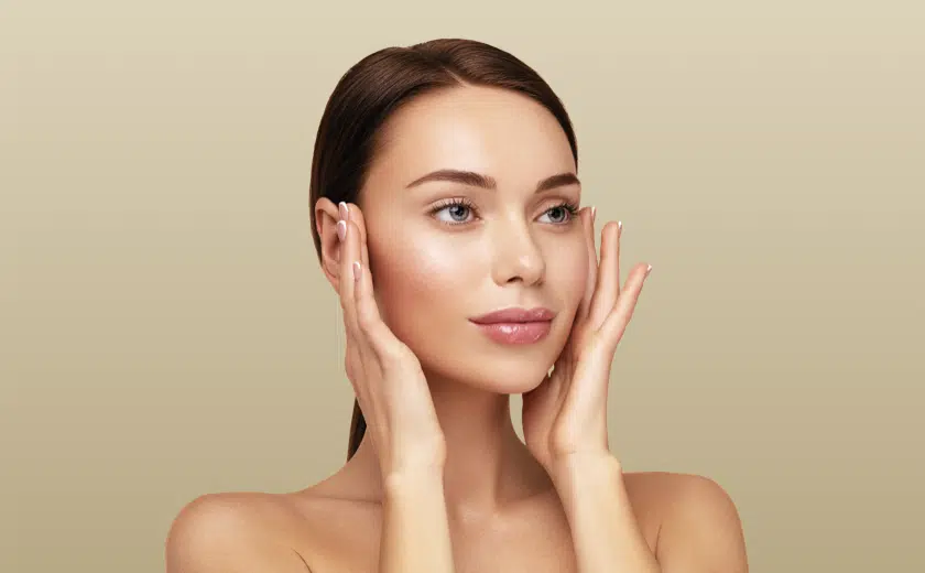 Pro MD Health Dermal Filler treatments: A youthful looking woman with pulled-back brown hair touches her face admiringly.